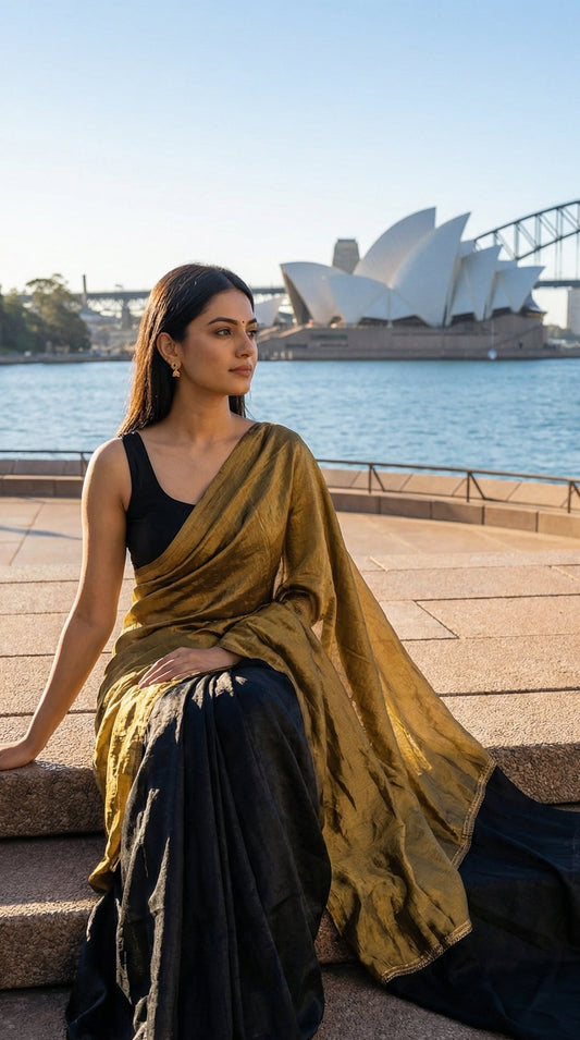 Woman in a antique golden Fendy silk saree with floral motifs and black contrast border, elegant festive wear, sitting on steps with the Sydney Opera House in the background.