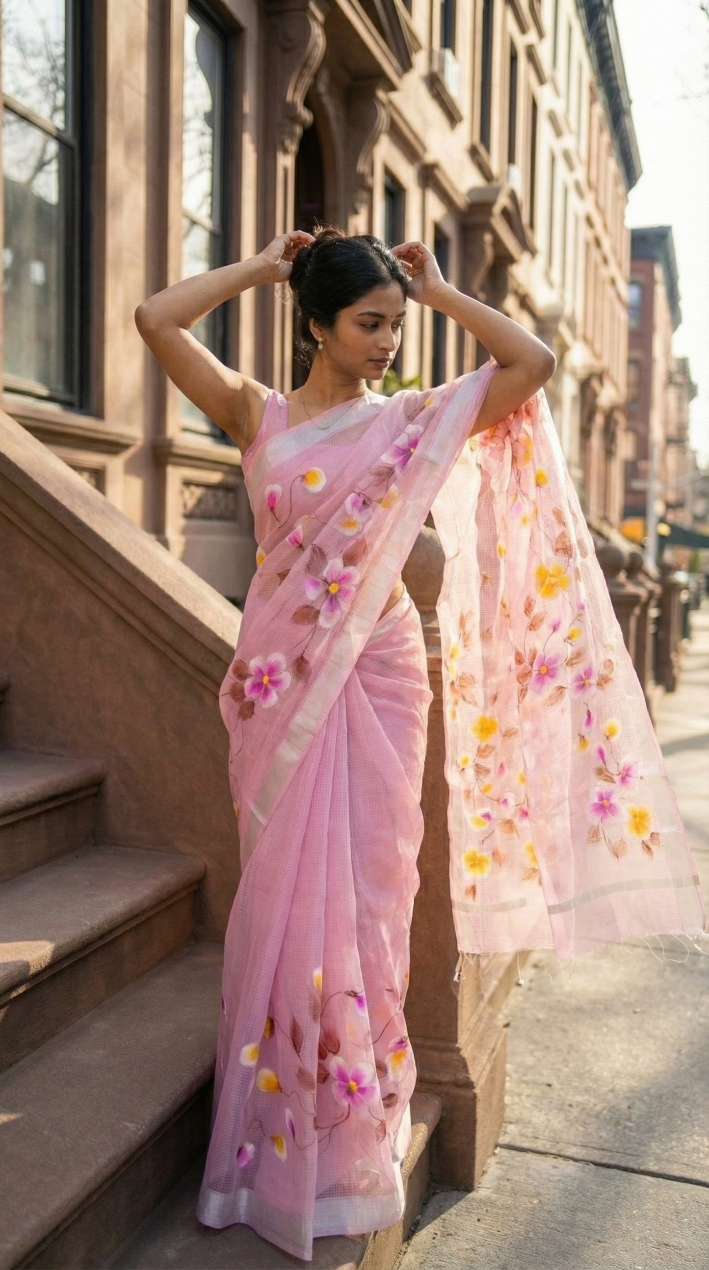 Woman in a pink-kota-doria-hand-painted-saree, standing on a city street.