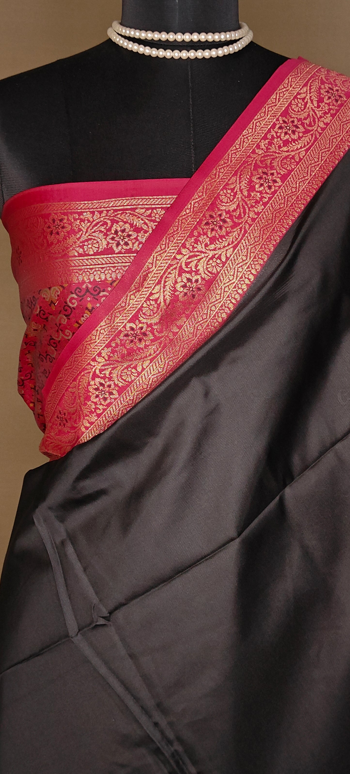 Black pure soft silk saree with magenta zari border and golden motifs, styled on mannequin showcasing the blouse piece in magenta color.