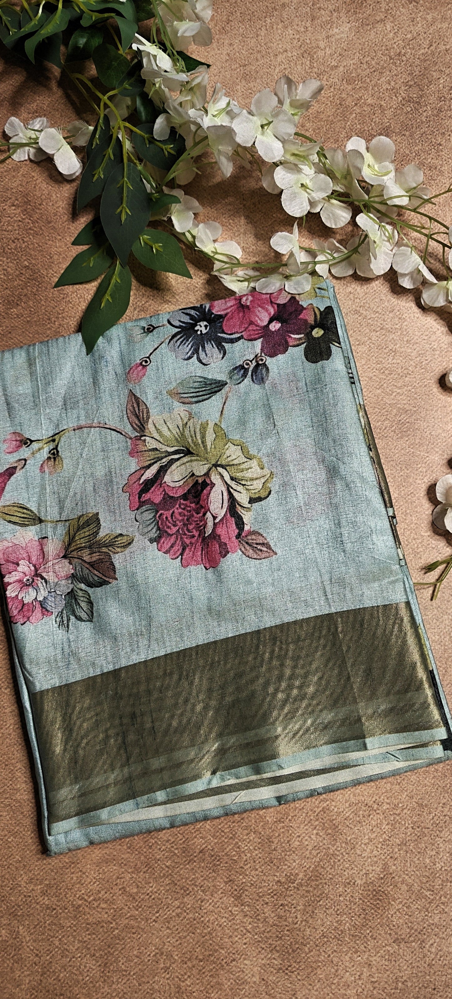 Sky blue viscose silk saree with floral accents, styled on mannequin with pearl necklace, perfect for festive wear.