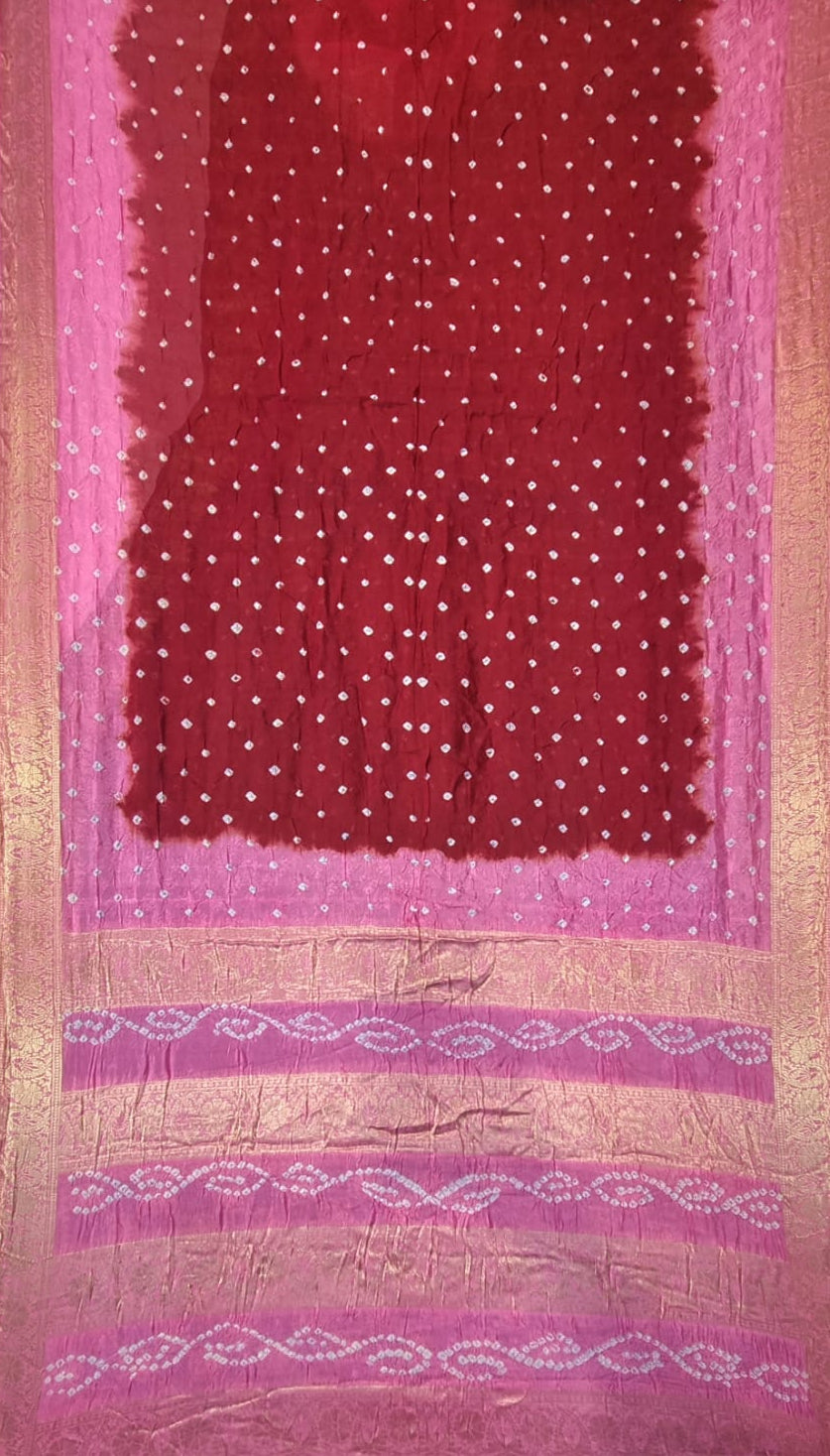 A pink and red fabric art silk saree with white dotted patterns, a pink border, and metallic gold woven decorative bands near the bottom.