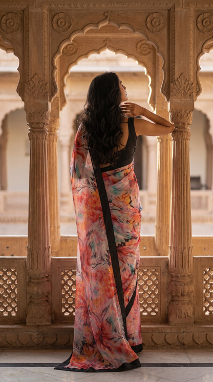 A back view of a woman looking out from an arched sandstone palace veranda, highlighting the sleek backline of her black blouse and the cascading printed chiffon pallu