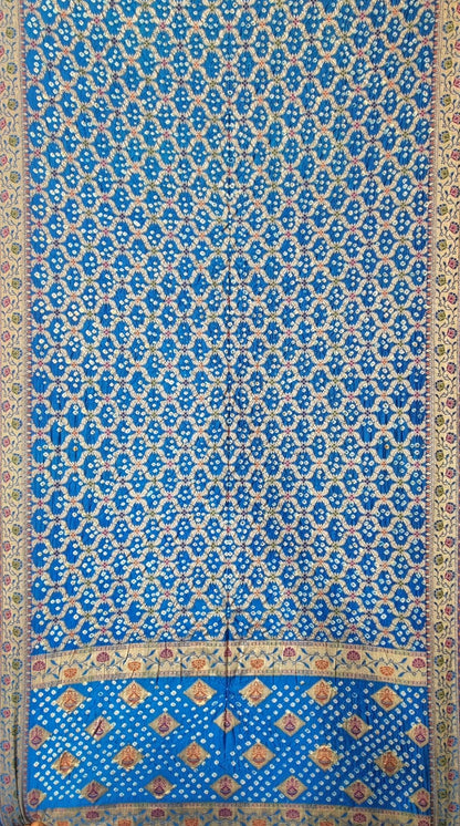 A blue patterned art silk saree with an intricate repeating floral motif and a decorative border, shown flat against a neutral background.