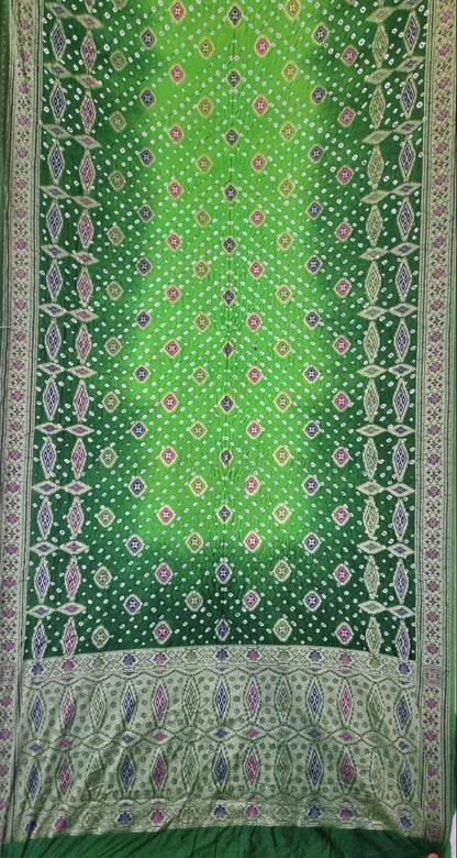 A Dhupiyan Silk with Bandhani & Jaal Zari - Green, featuring intricate geometric and floral motifs in purple, pink, and white, with a wide decorative border at the bottom.