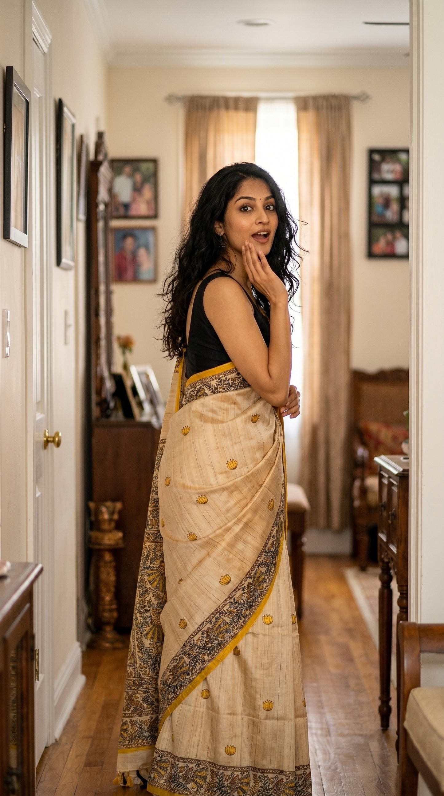 An over-the-shoulder look of a woman standing in a home hallway, highlighting the elegant yellow lotus print layout on a beige Tussar silk saree