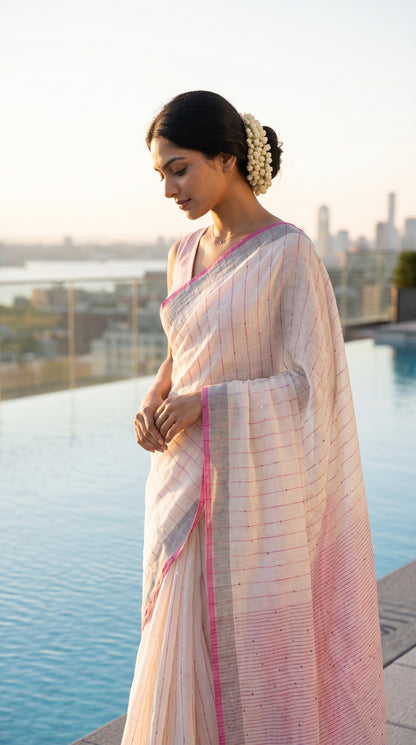Model looking down thoughtfully while posing on an infinity pool deck at sunrise, showcasing the delicate shimmer of sequins on a white khadi linen drape
