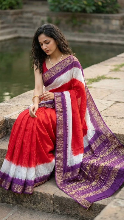 Woman in a magenta modal silk saree with purple zari border sitting by a pond.