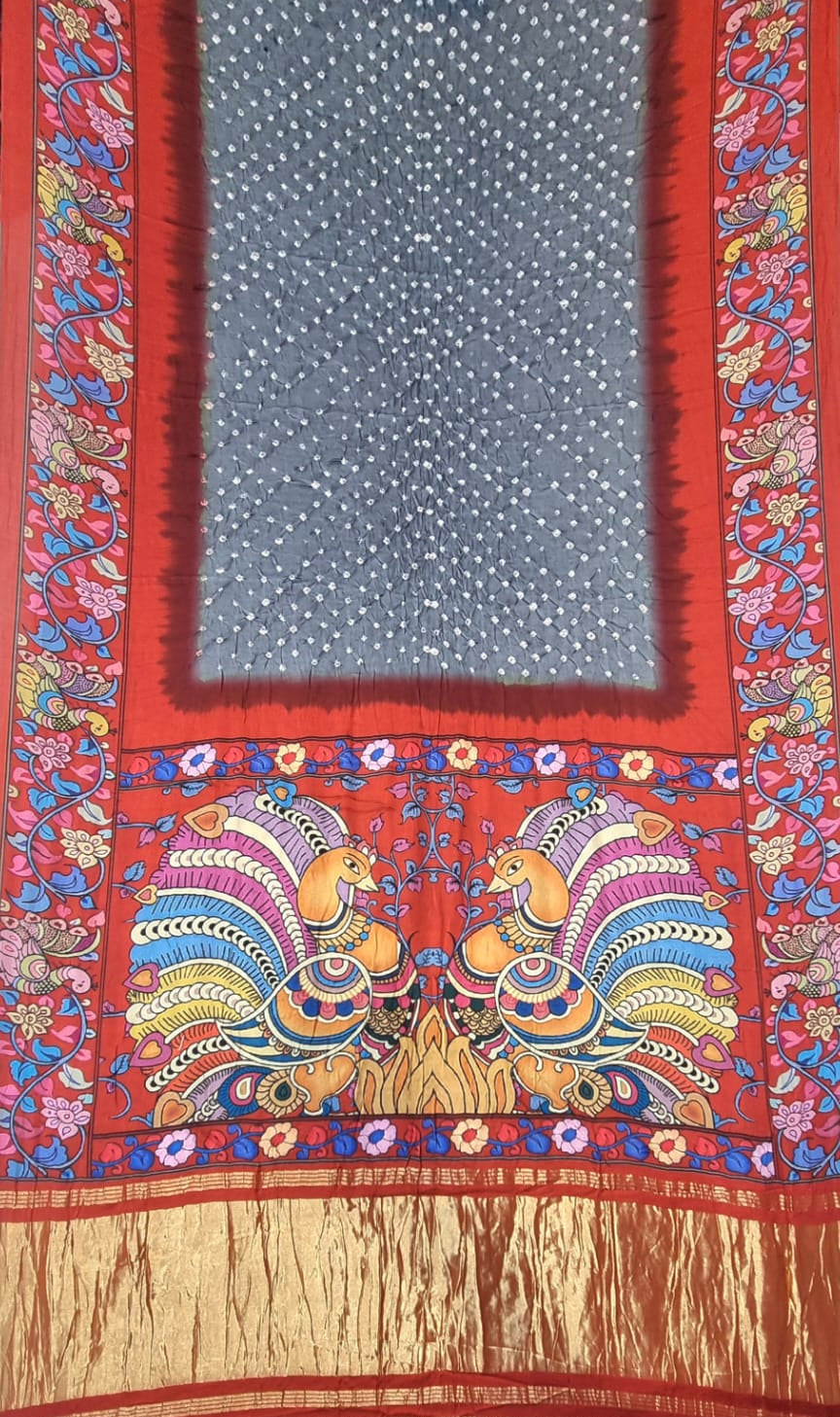 A Modal Silk with Bandhani Kalamkari Print Border - Grey with Red saree panel featuring a central blue-grey field with white dots, surrounded by a red border and decorated with colorful peacock motifs and gold Zari detailing.