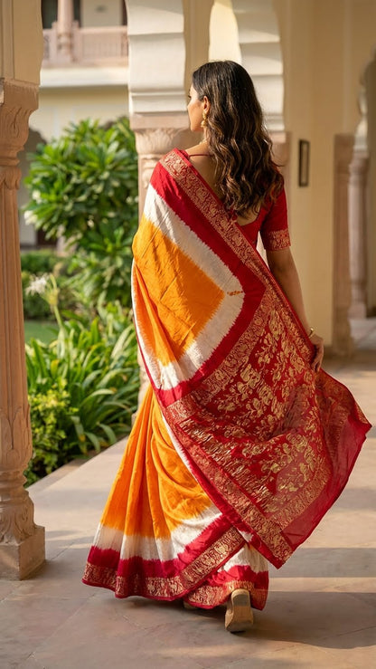 Woman in a orange & magenta modal silk saree with zari border walking outdoors.
