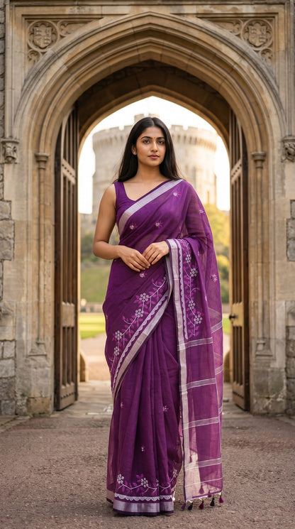 Full-length view of a woman standing under a grand stone archway, showcasing the structured drape and white floral vine embroidery of a purple cotton linen saree