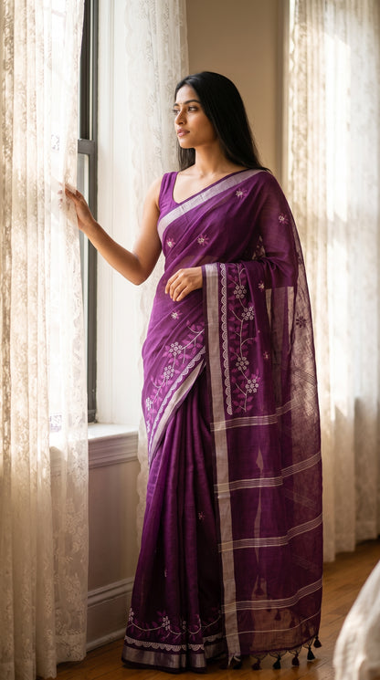 A model looking out a window beside lace curtains, highlighting the silver Zari border and delicate floral motifs on a purple cotton linen saree