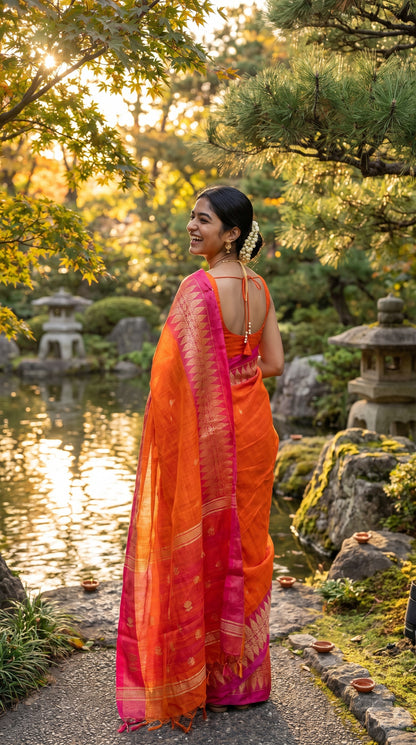 A rear view of a laughing woman adorned with a fresh gajra walking along a stone path by a peaceful garden pond, highlighting the gorgeous gold leaf embroidery on the magenta pallu of her orange linen saree.