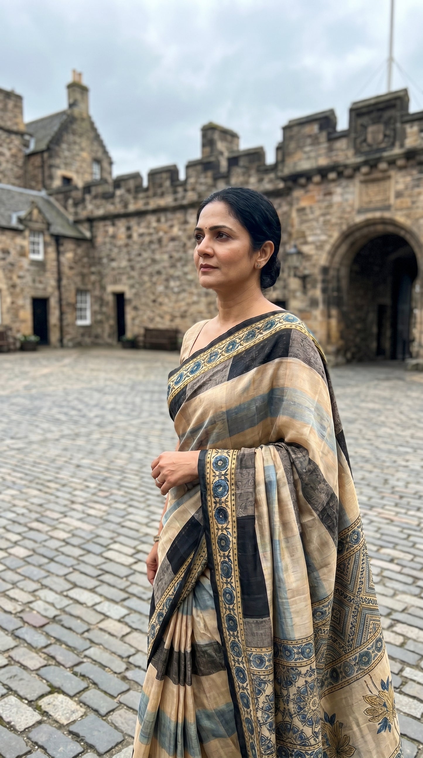 Woman in a saree standing in front of a castle