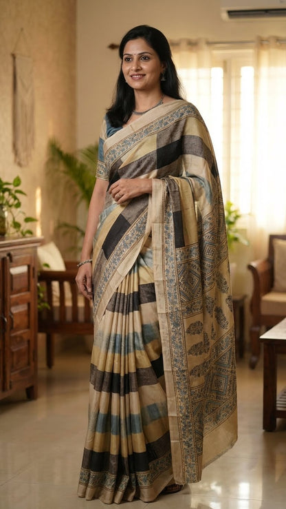 Woman wearing a Ajrakh Modal Silk Saree – Beige, Black & Blue with Floral Border saree in a well-lit room with furniture and plants.