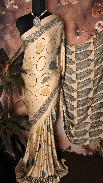 Ajrakh Modal Silk Saree – Beige with Golden & Olive Circular Motifs and Feather Pallu saree with intricate patterns on a mannequin against a floral background.