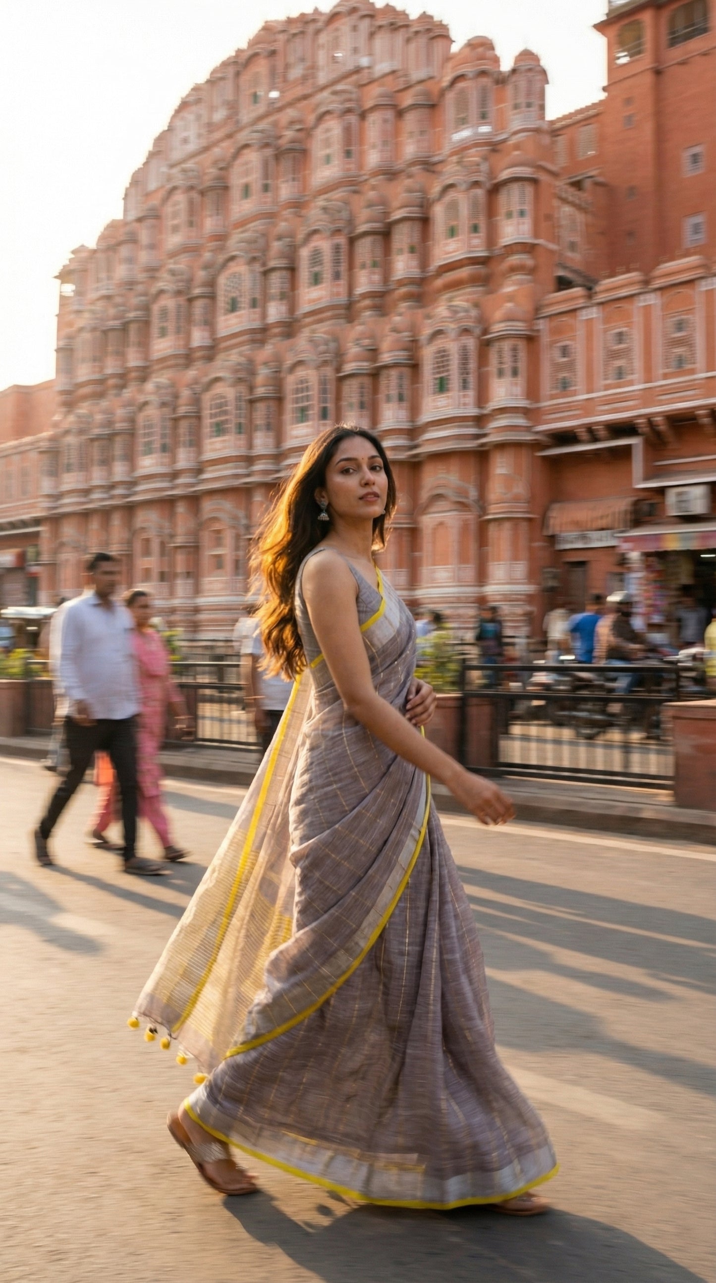 Woman in a ash-grey-cotton-linen-saree, walking in front of a historic building with intricate architecture.