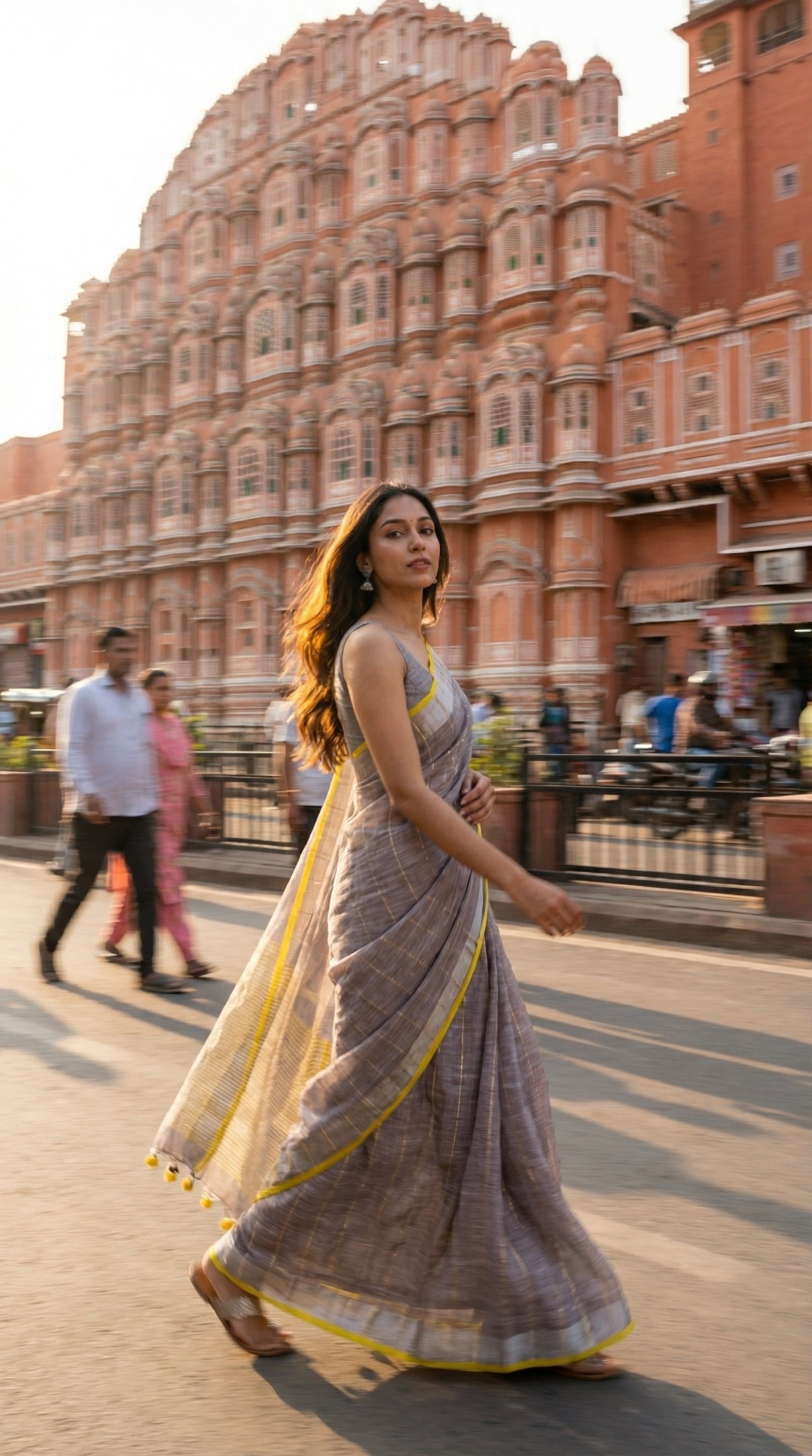 Woman in a ash-grey-cotton-linen-saree, walking in front of a historic building with intricate architecture.