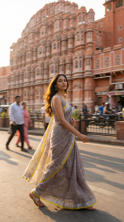 Woman in a ash-grey-cotton-linen-saree, walking in front of a historic building with intricate architecture.