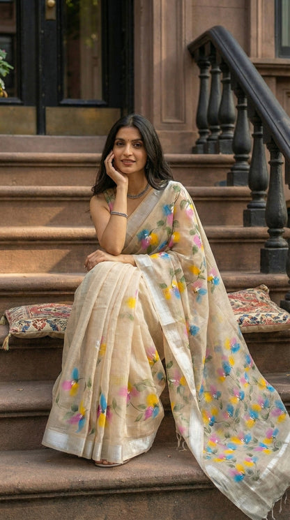 Woman wearing a beige-hand-painted-cotton-saree, sitting on steps outdoors