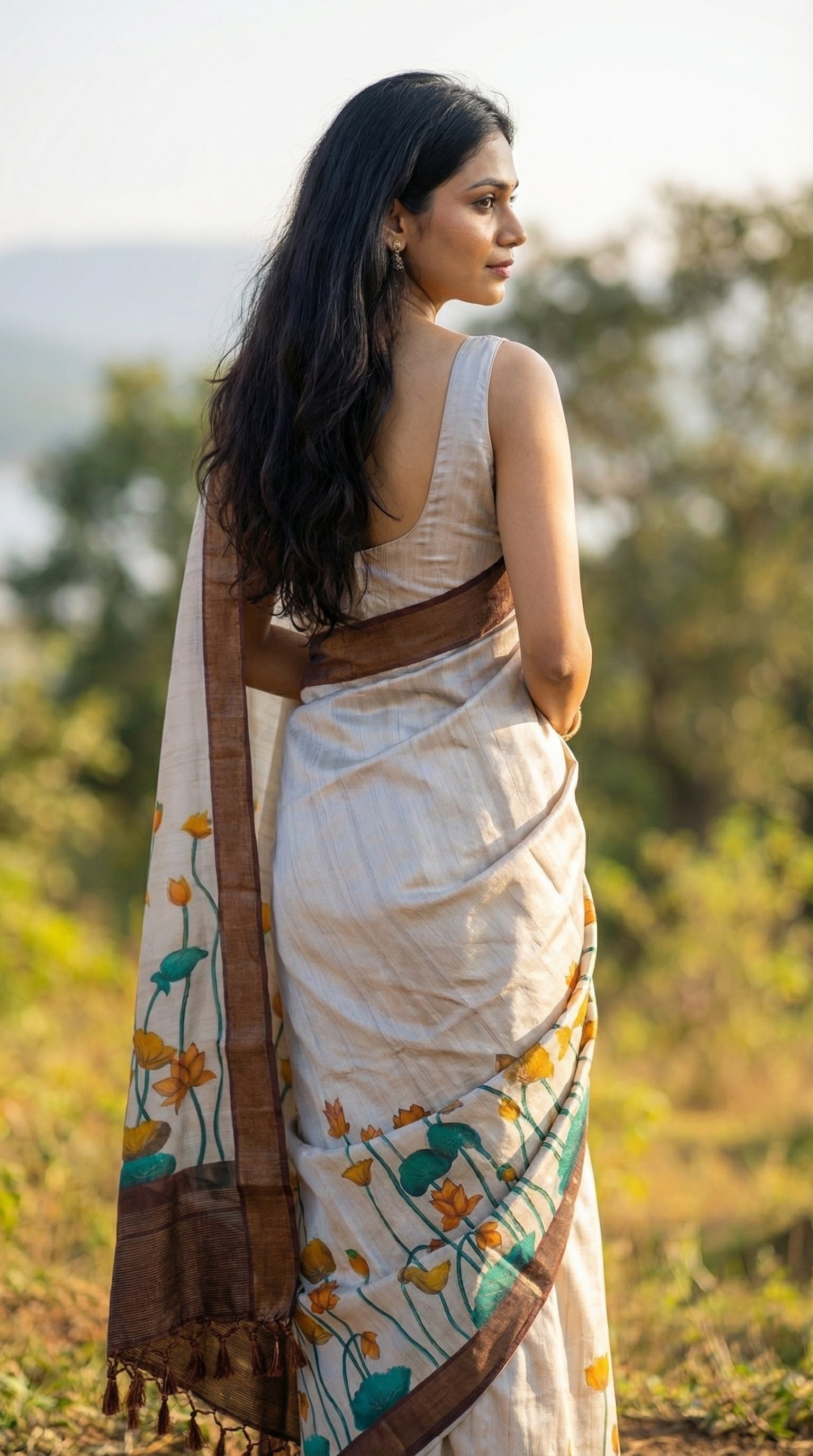 Woman in a beige-viscose-silk-brown-floral-saree, standing in a natural setting