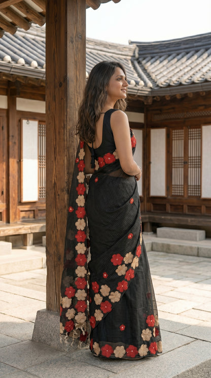 Woman in a black-mirror-work-kota-saree, standing in a traditional Korean house courtyard.