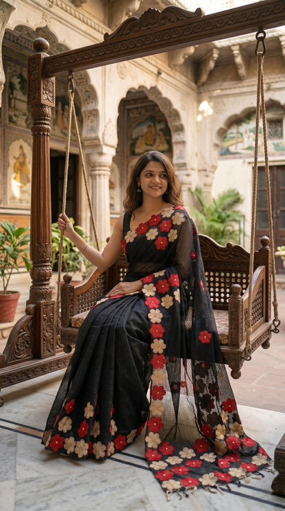 Woman in a black-mirror-work-kota-saree, sitting on a wooden swing in an ornate indoor setting.