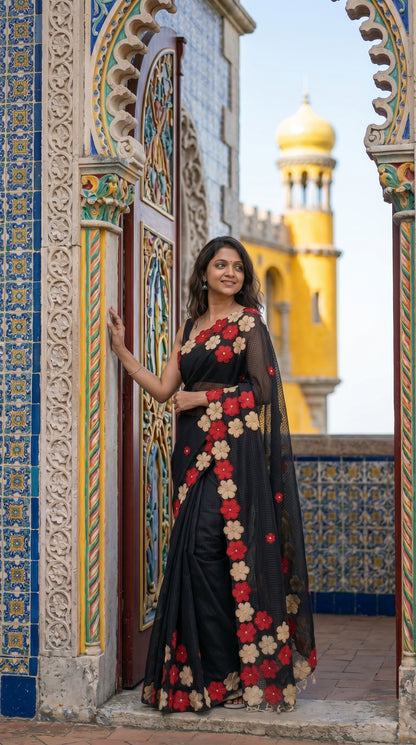 Woman in a black-mirror-work-kota-saree, standing in front of a colorful architectural background.
