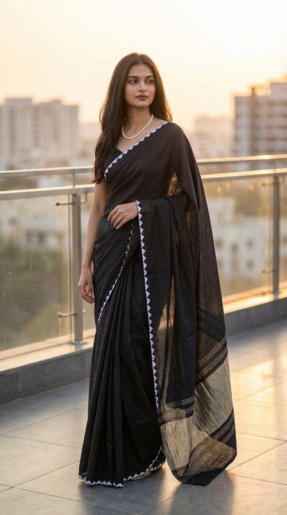 Woman in a black-modal-silk-saree-lagdi-patta-pallu, standing on a terrace with the city blurred background