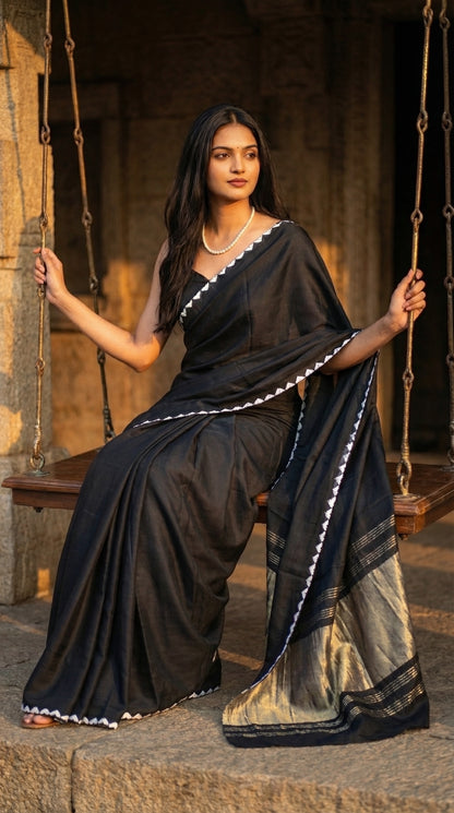 Woman in a black-modal-silk-saree-lagdi-patta-pallu, sitting on a jhula in an old house setup.