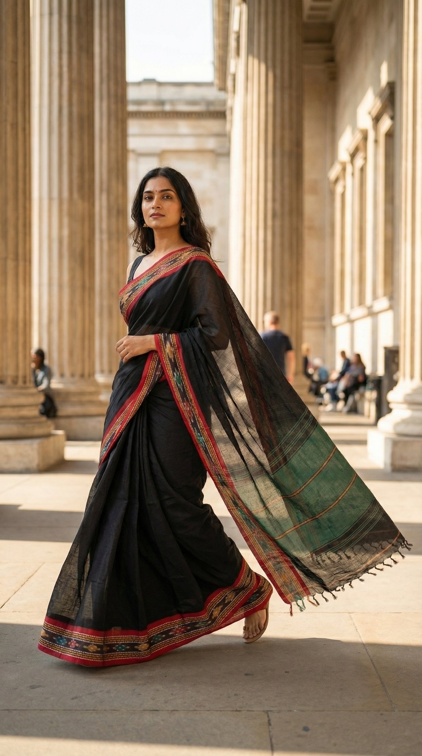 Woman in a black-mul-cotton-ikat-saree, standing in front of classical architecture.