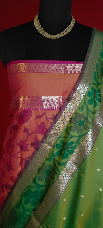 Green blended silk saree with elegant zari border and festive drape on a mannequin along with a flower vase against red background.