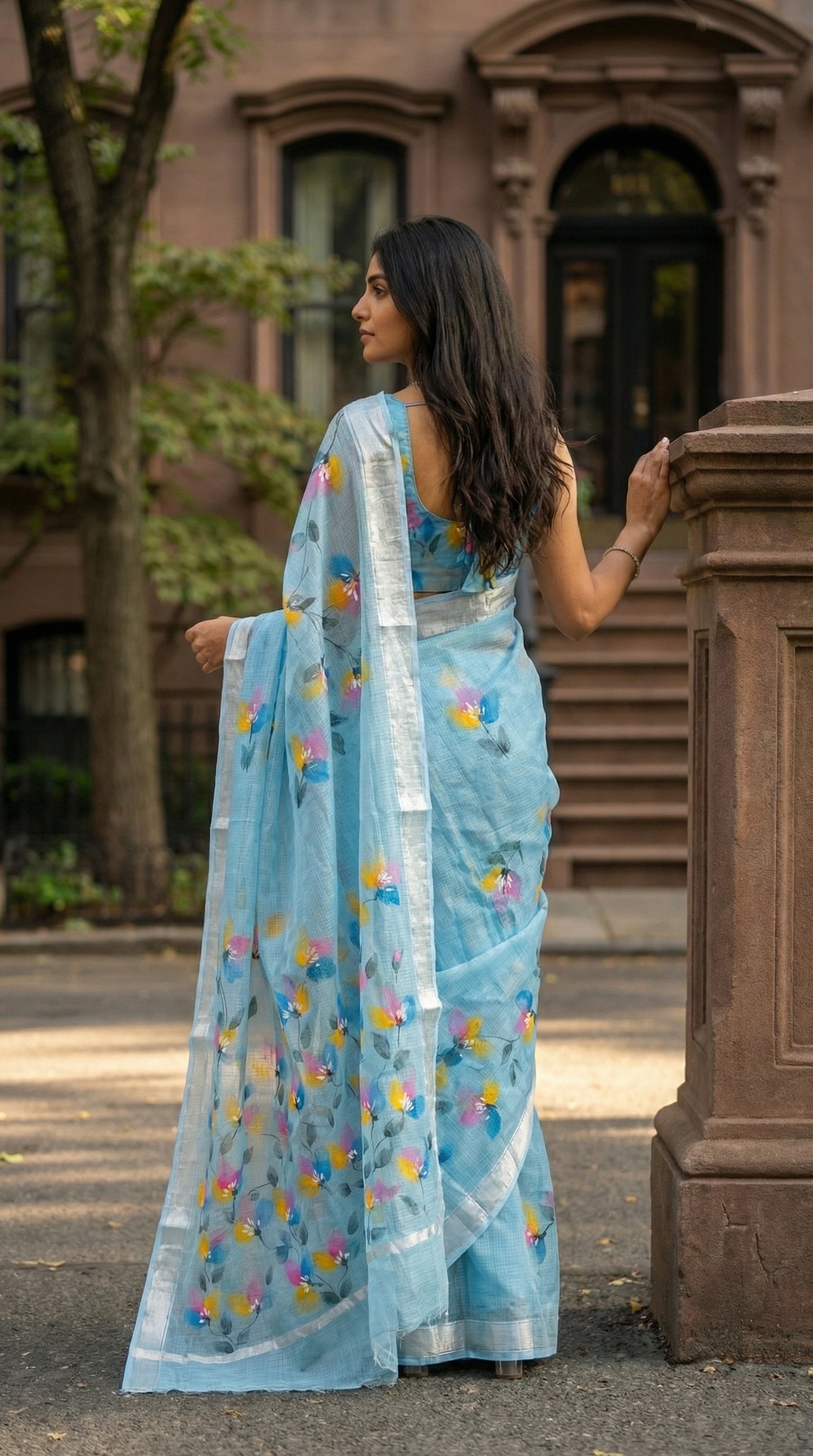 Woman in a blue-hand-painted-cotton-saree, standing outdoors.
