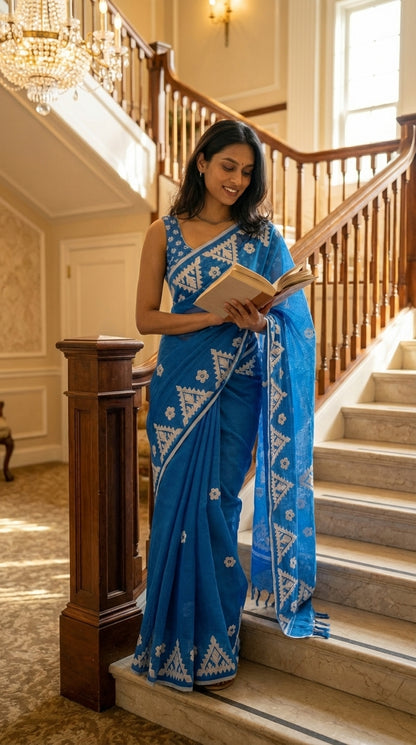 Woman in a blue-white-applique-kota-saree, reading a book on a staircase