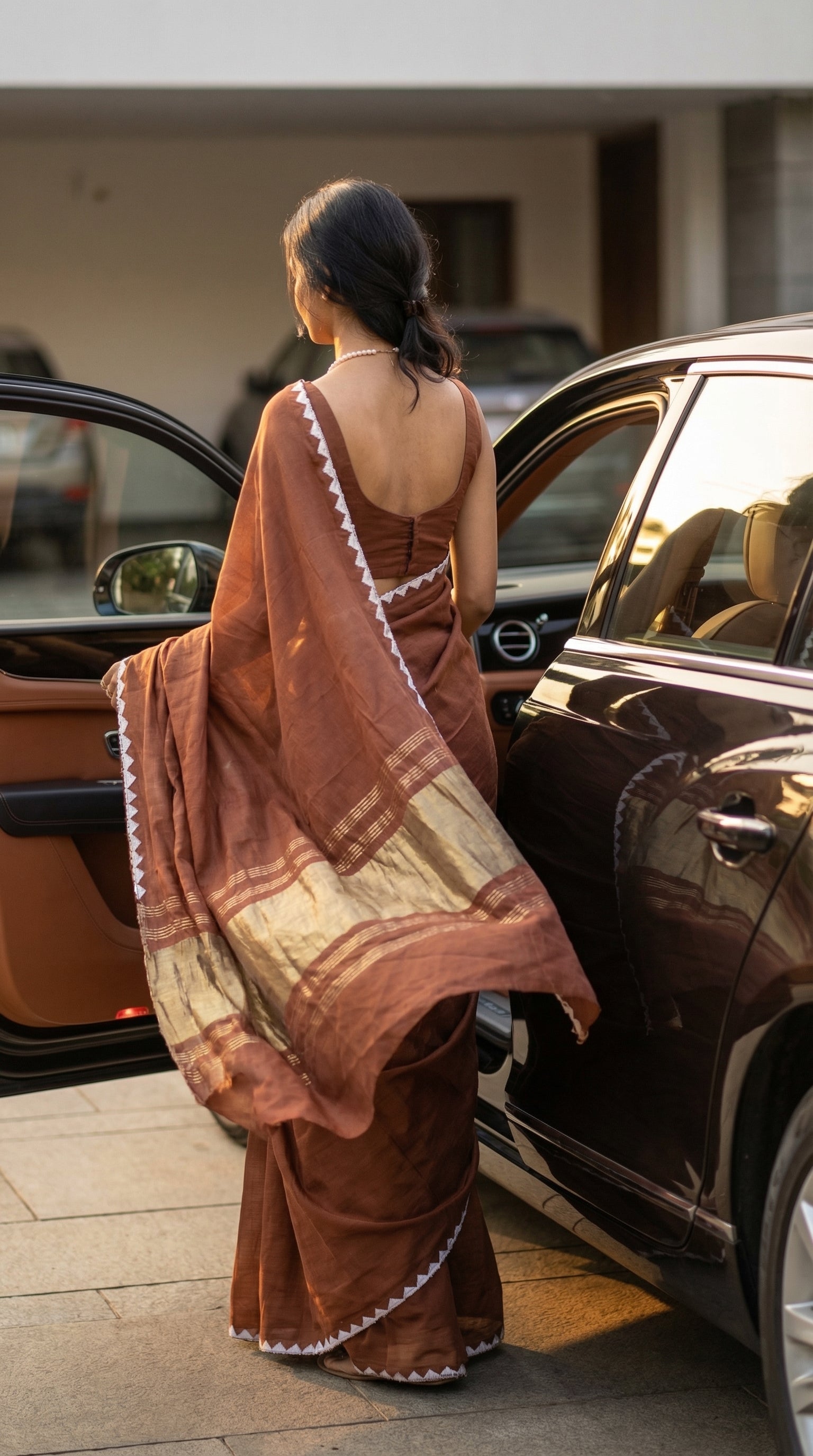 Woman wearing a chocolate-brown-modal-silk-saree-lagdi-patta-pallu, getting into a car