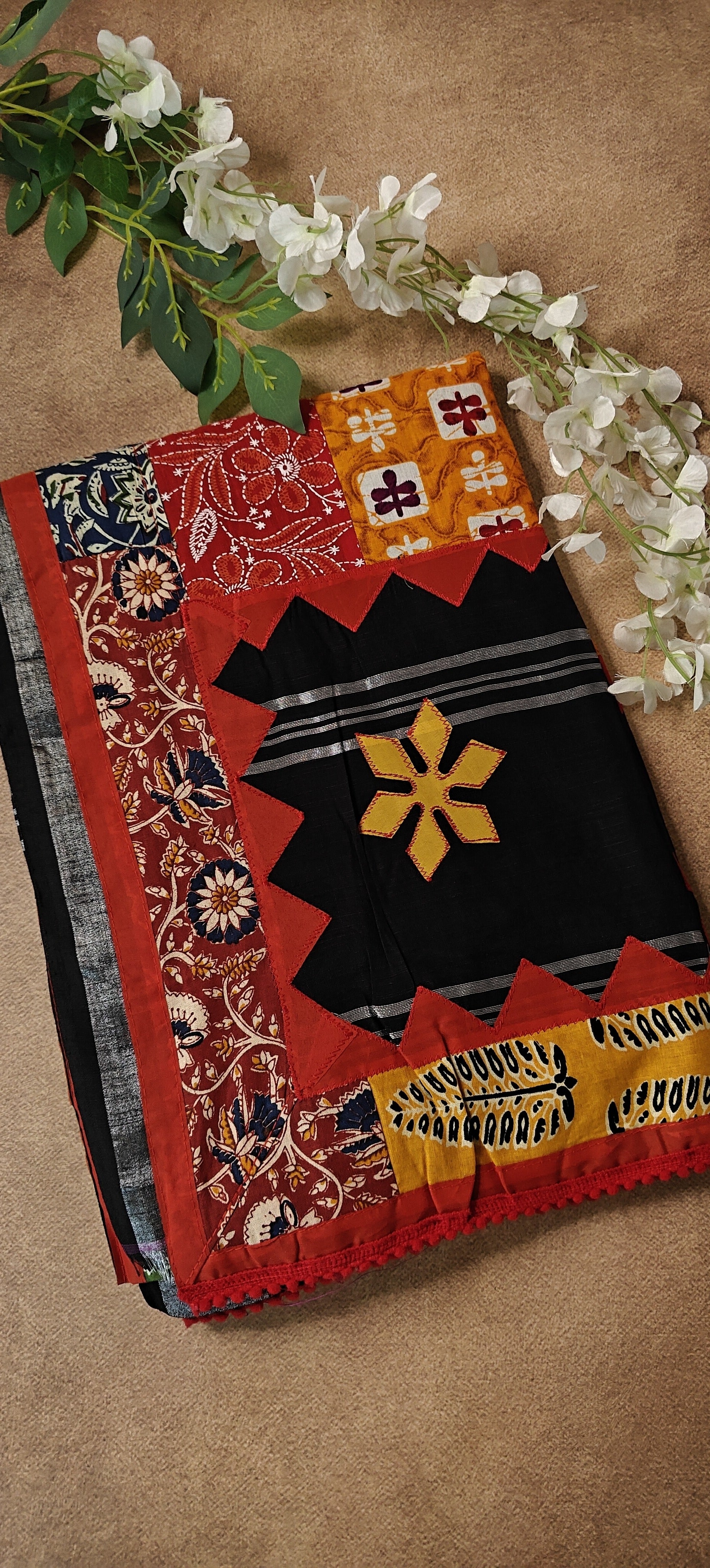 Black cotton saree with bold appliqué designs and traditional motifs, elegant ethnic wear for festive occasions.
