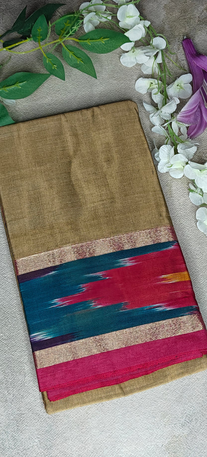 Golden yellow cotton saree with multicolor border and metallic accents, folded with white flowers with neutral background.