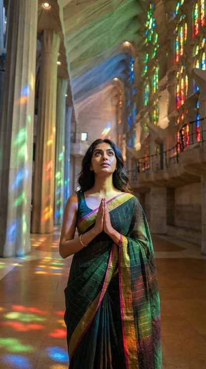 Woman in a dark-green-cotton-linen-saree-zari, standing in a cathedral with stained glass windows casting colorful patterns on the floor.