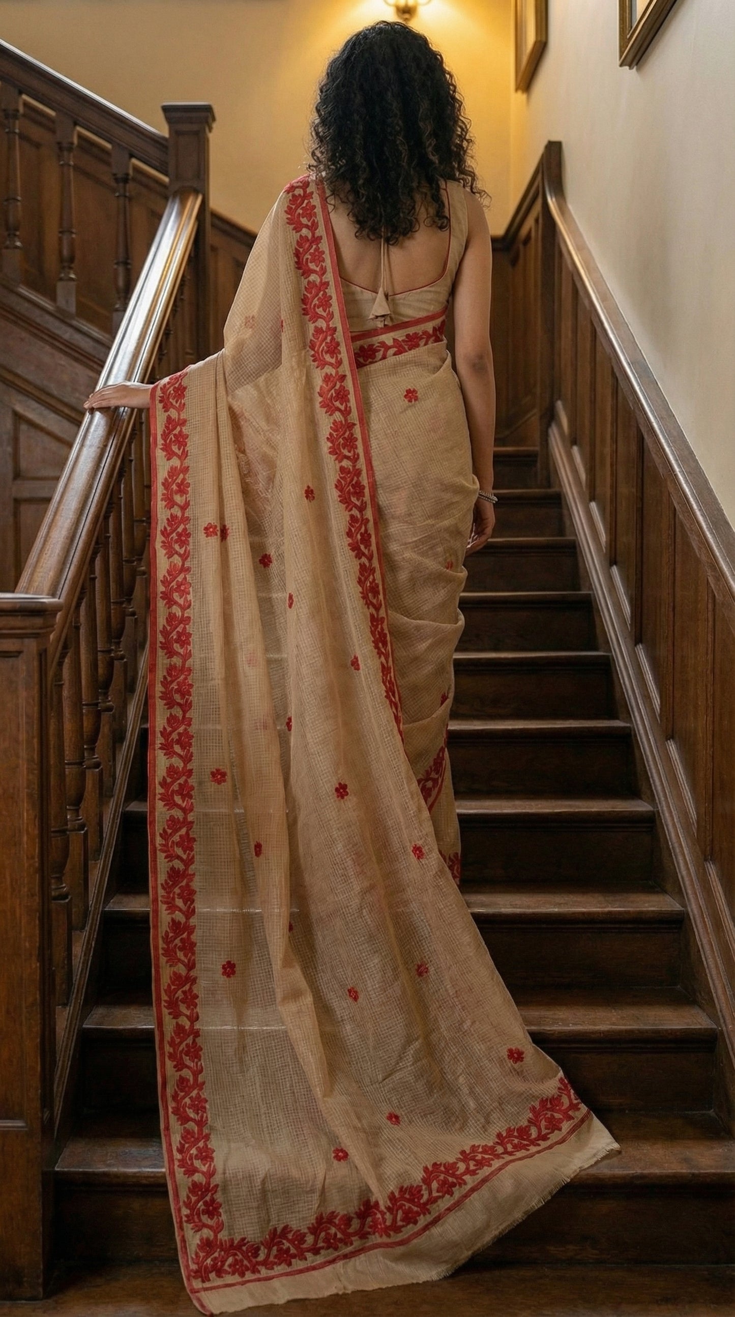 Woman in a golden-kota-doria-saree, walking up a staircase.