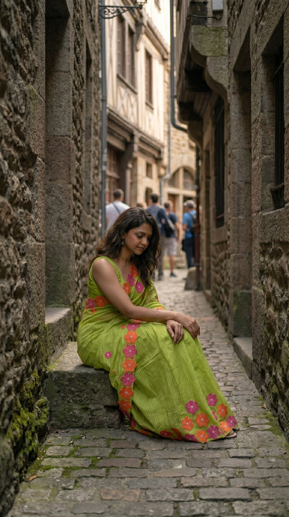 Woman in a green-mirror-work-kota-saree, sitting in a narrow stone alleyway.
