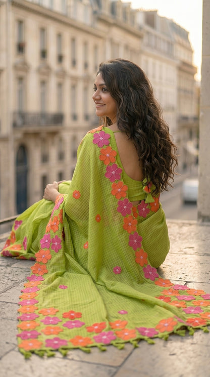 Woman in a green-mirror-work-kota-saree, sitting on a stone ledge in an urban setting.