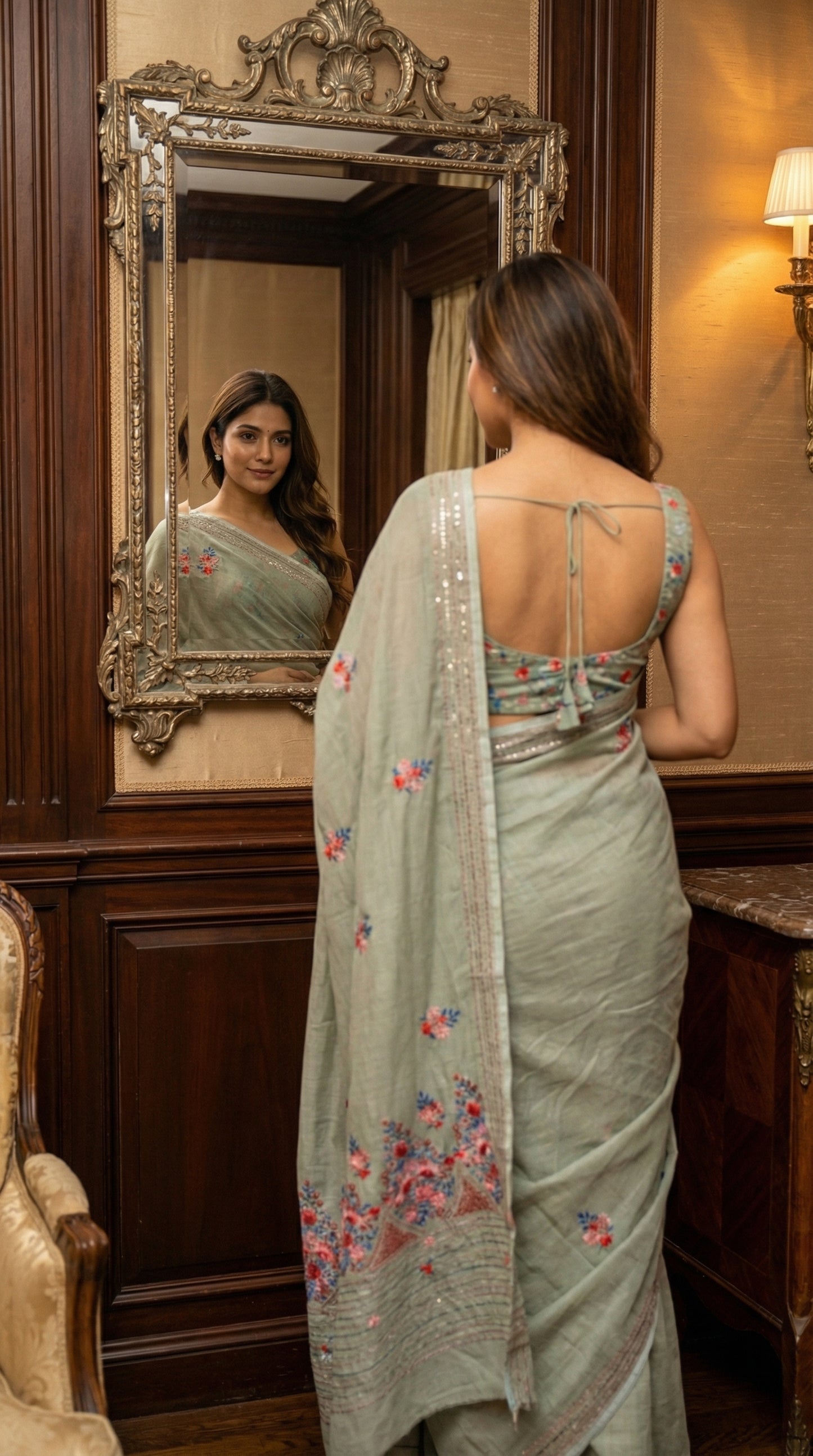 Woman wearing a grey-chanderi-kantha-saree, looking at herself in a mirror in an elegant room.