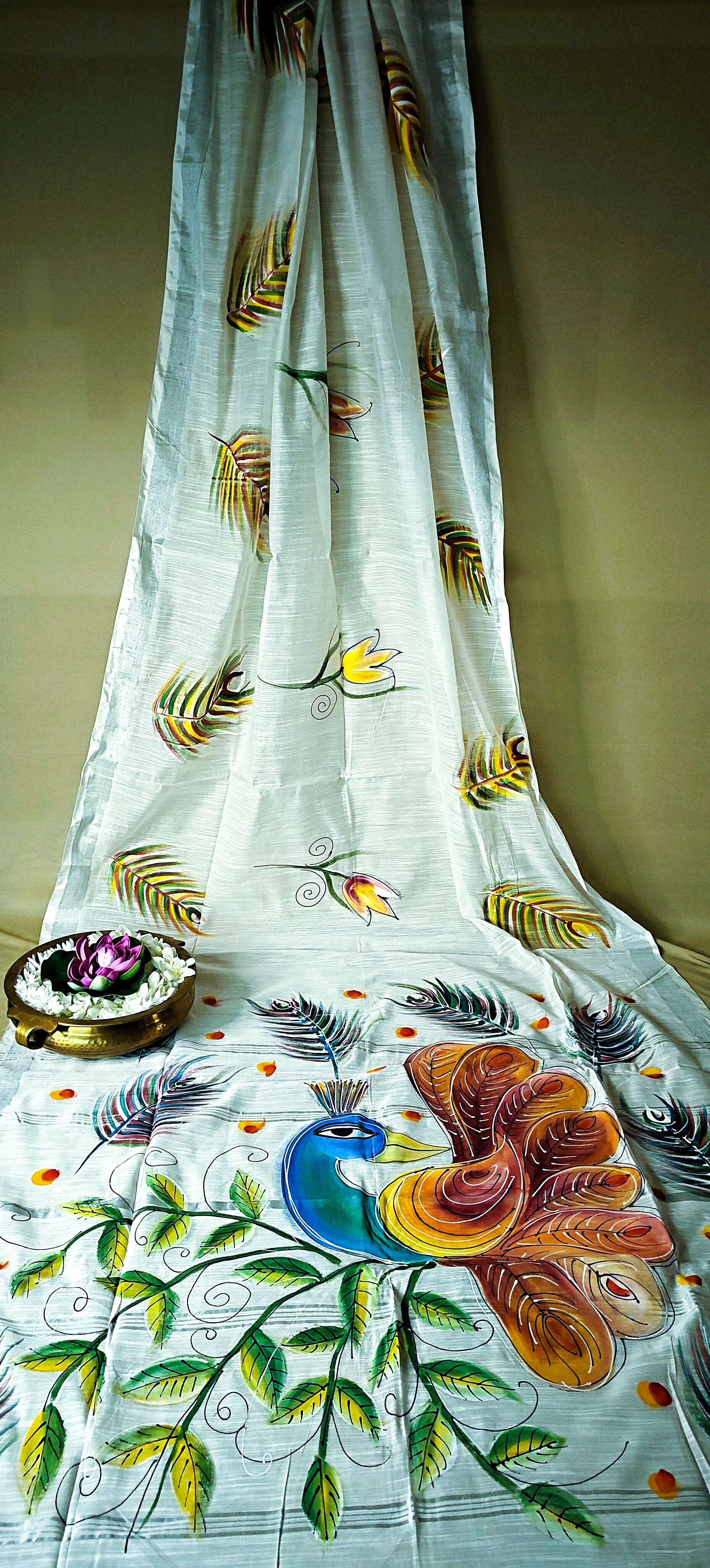 White cotton saree with vibrant hand-painted peacock and floral motifs, breathable artisan ethnic attire.