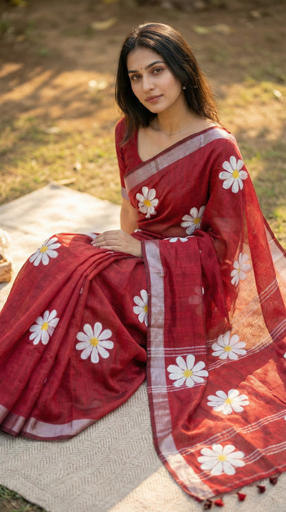 Woman wearing Red cotton saree featuring hand-painted sunflower design with white and yellow petals, sitting outdoors.