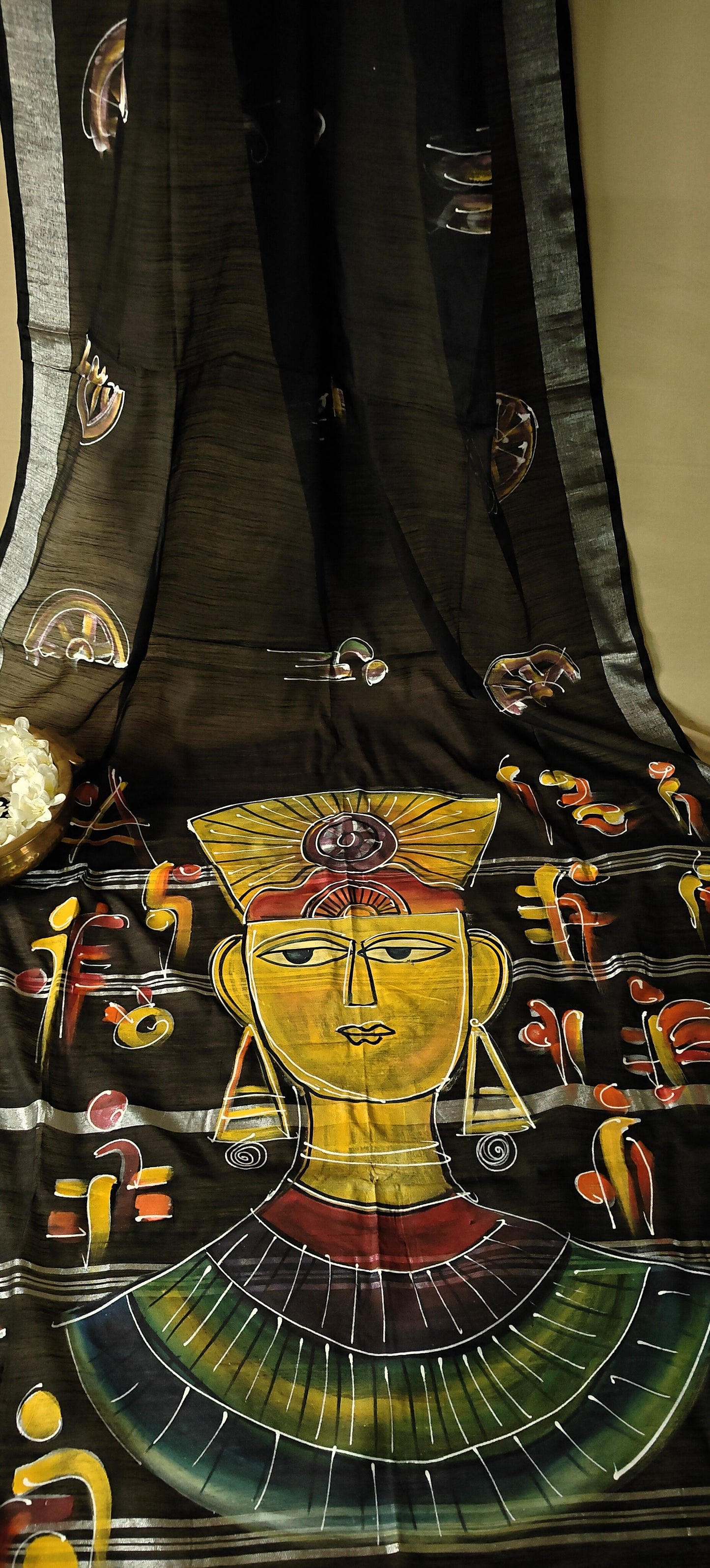 Black cotton saree featuring hand-painted tribal-inspired abstract face with geometric motifs, handcrafted Indian saree.