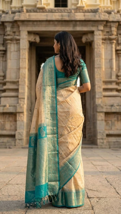 Woman in a beige Hasthkala blended silk saree featuring a royal blue gold zari border and temple motifs standing in front of an ancient temple.