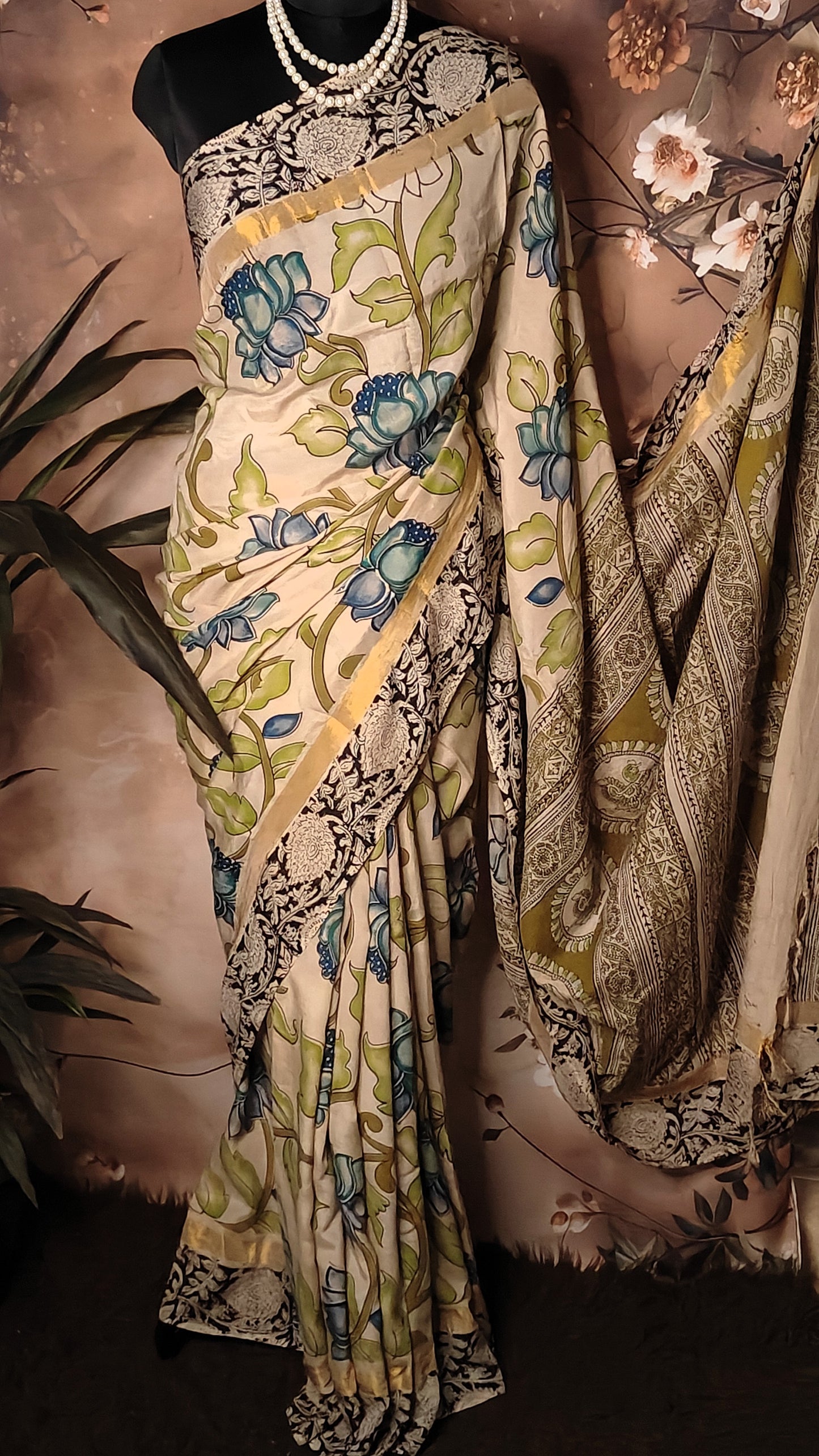 Kalamkari Print Silk Saree – Cream with Blue-Green Floral Motifs and Zari Border draped on a mannequin.