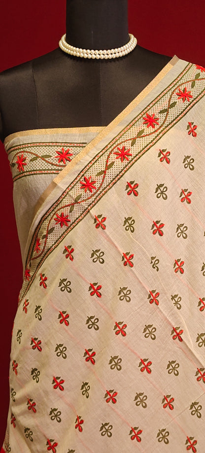 Handcrafted Kantha stitched silk blend saree in cream with red and green floral embroidery on a mannequin showcasing the blouse piece against a red background.