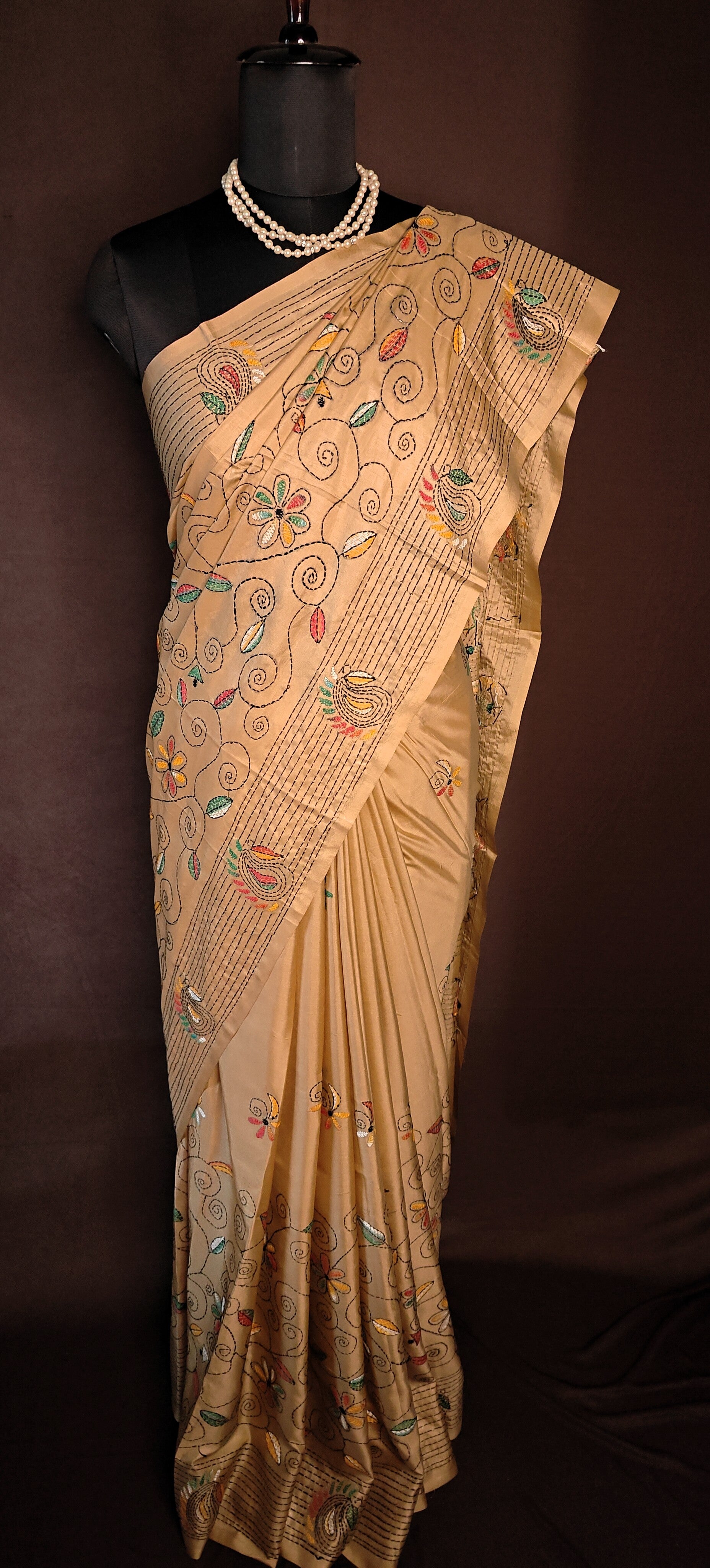 Handcrafted Kantha-Stitched Cotton Saree – Gold with Multicolor Floral & Paisley Embroidery on a mannequin with dark background.