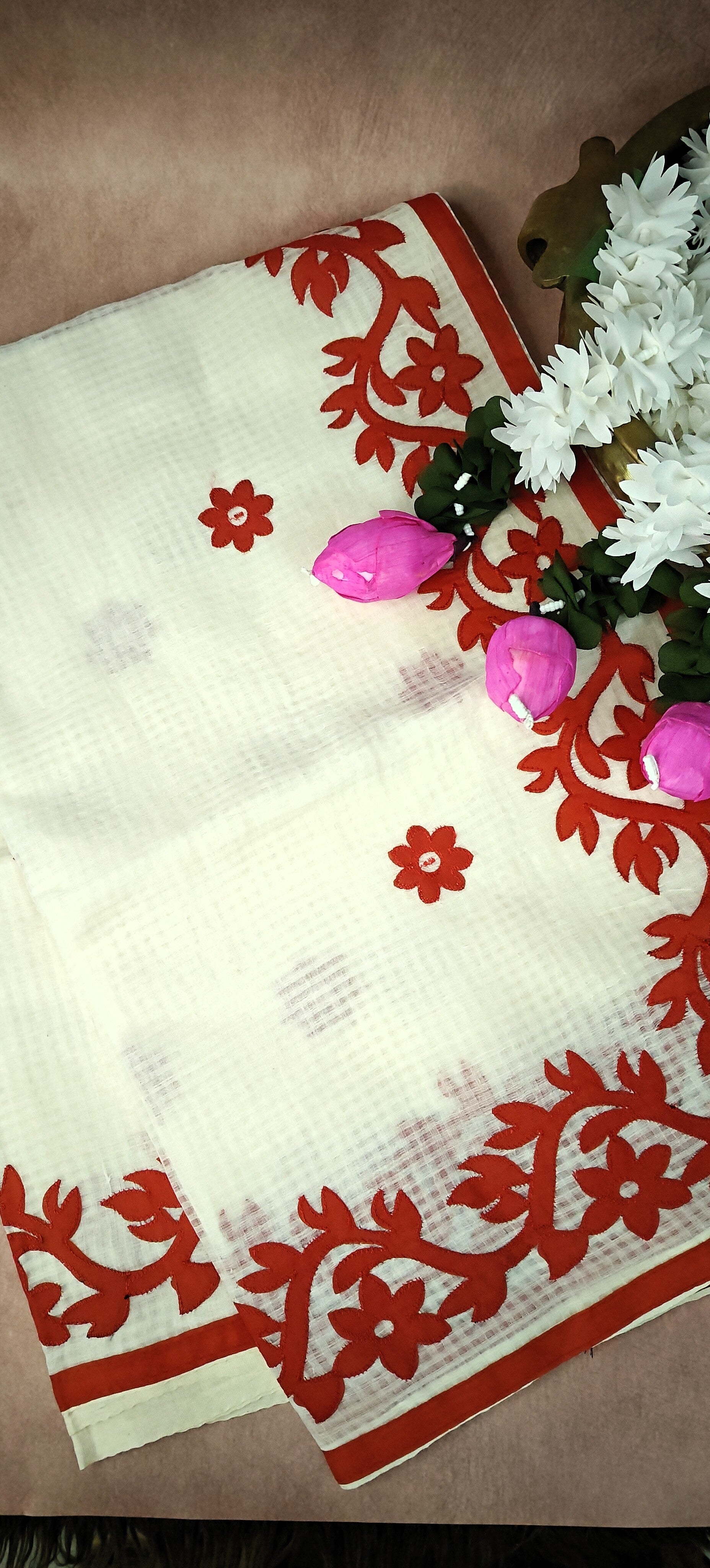 White Kota saree featuring intricate appliqué work with floral and paisley motifs in red, traditional festive attire.