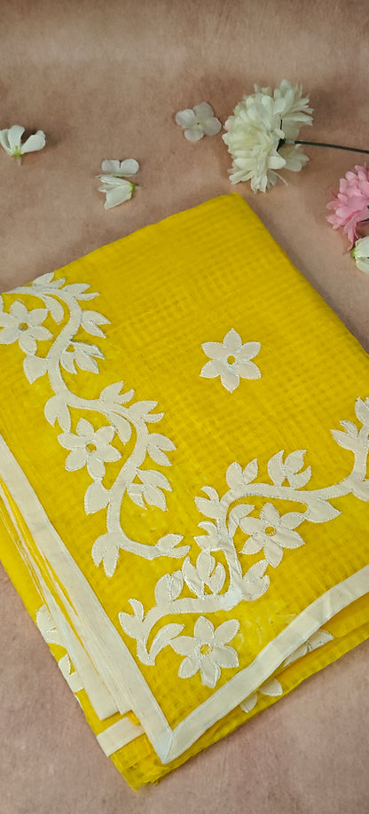 Yellow Kota saree with white floral appliqué embroidery, lightweight handcrafted Indian ethnic wear.